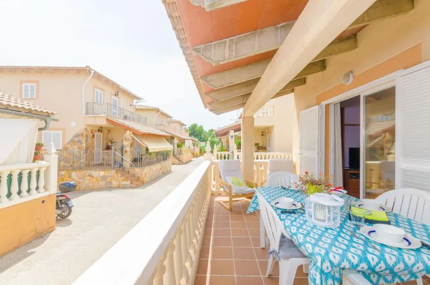 Una terraza cubierta tiene una mesa de comedor junto a varias viviendas.