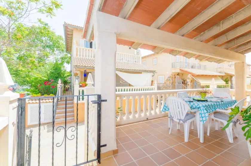 Una terraza exterior cubierta con suelo de baldosas, mesa de comedor y asientos.