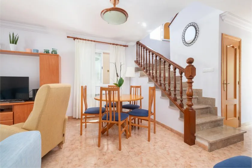 Un comedor con una mesa de madera y sillas junto a una escalera.