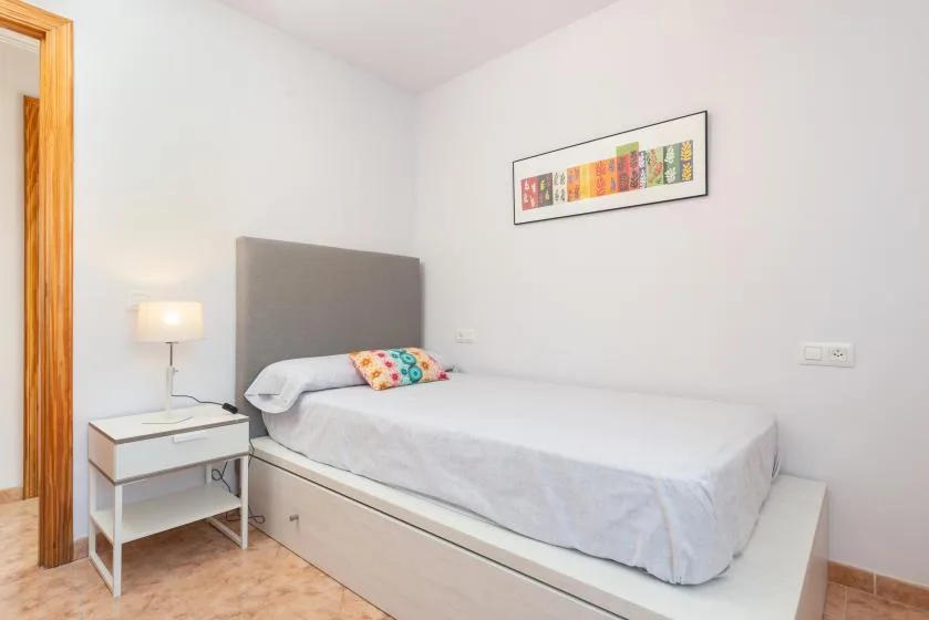 Un dormitorio con una cama individual, una mesita de noche y un cuadro en la pared.
