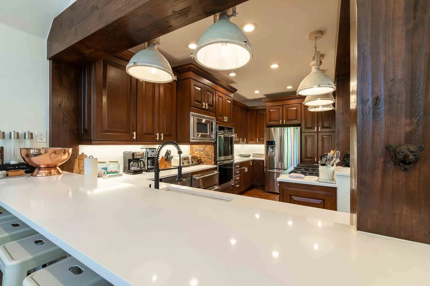 Una cocina amplia con gabinetes de madera oscura y una extensa encimera blanca.