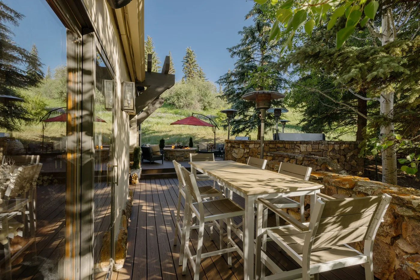 Una zona de comedor al aire libre con una mesa larga y sillas sobre una terraza de madera.
