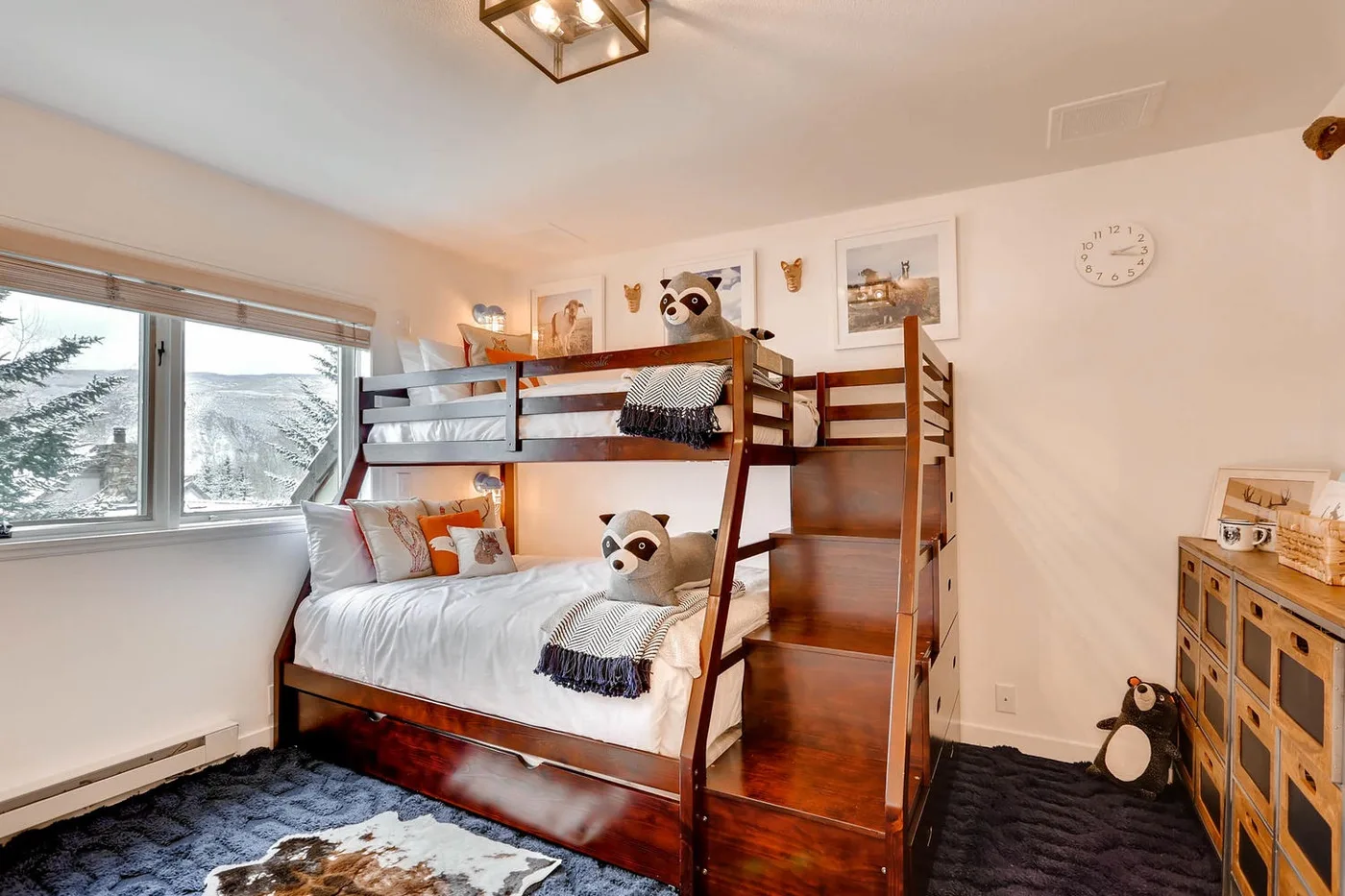 Una litera ocupa un dormitorio luminoso, junto a una gran ventana con vistas nevadas.