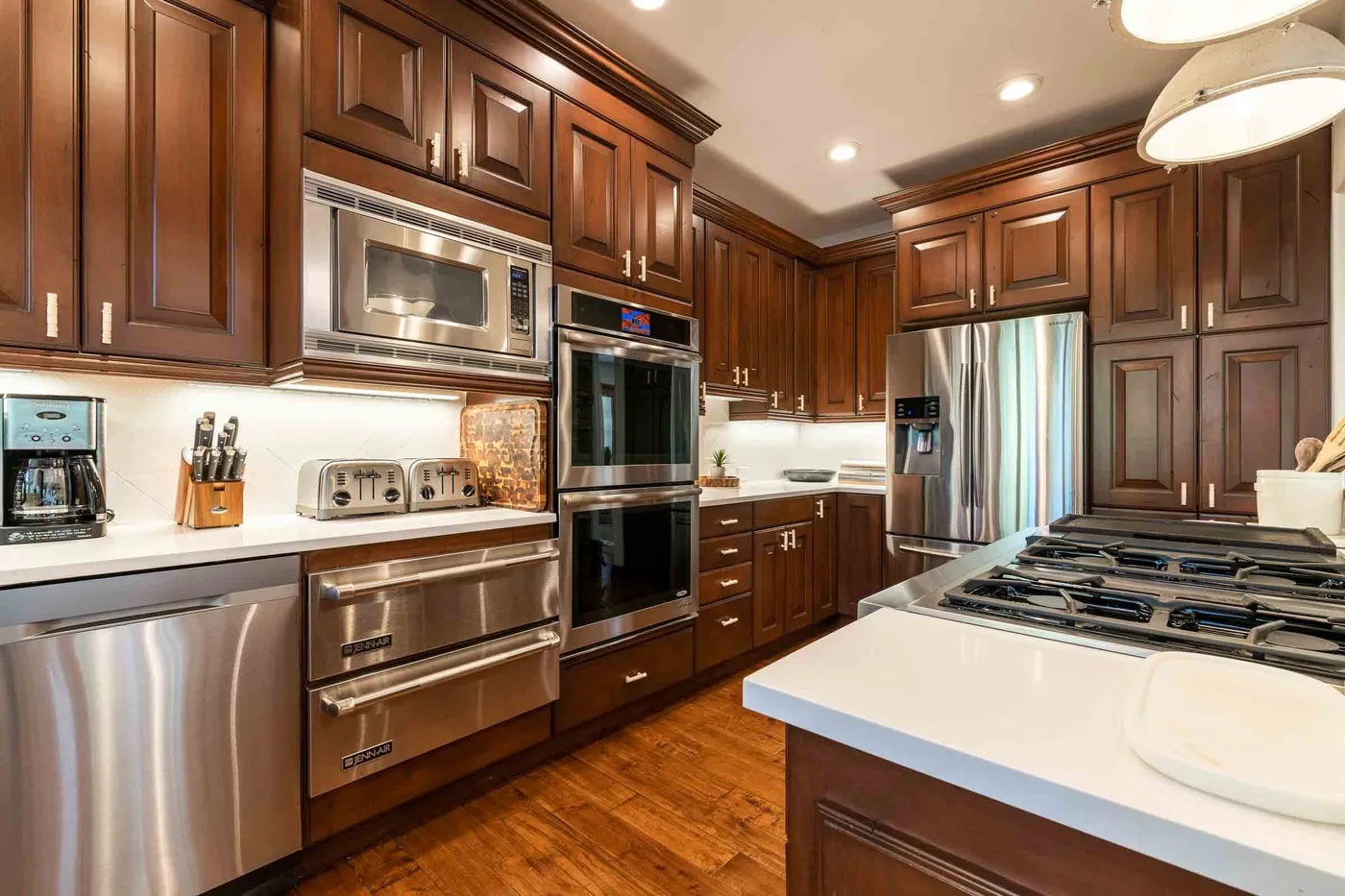 Una cocina amplia con gabinetes de madera oscura, electrodomésticos de acero inoxidable y una isla grande.