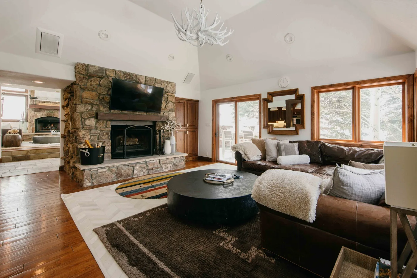 Una sala de estar con chimenea de piedra, asientos y ventanas grandes.