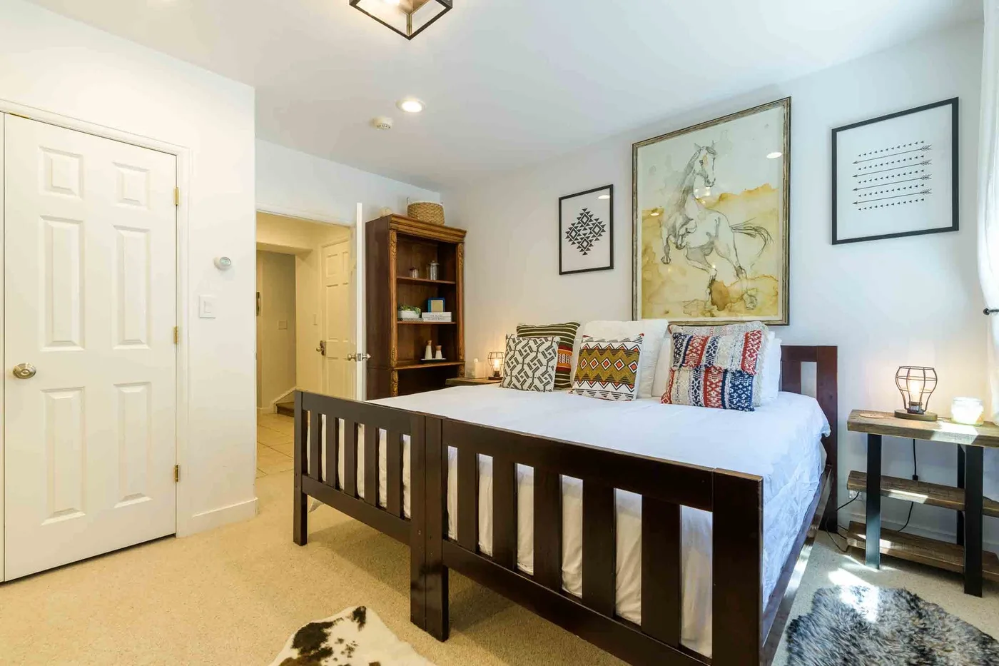 Un dormitorio con una cama de madera oscura, almohadas estampadas y cuadros en la pared.