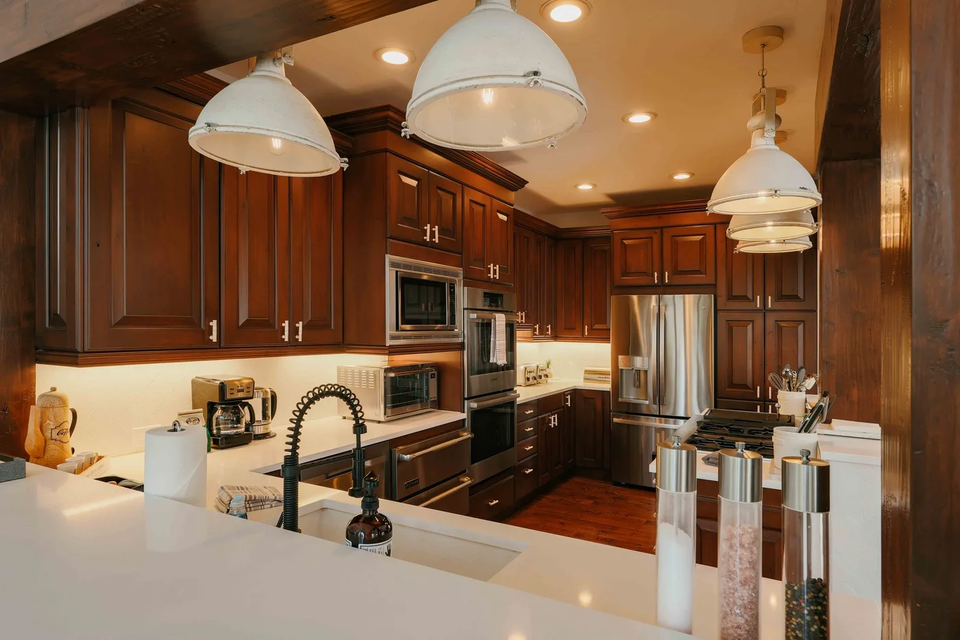 Una cocina con gabinetes de madera oscura, electrodomésticos de acero inoxidable y una encimera amplia.