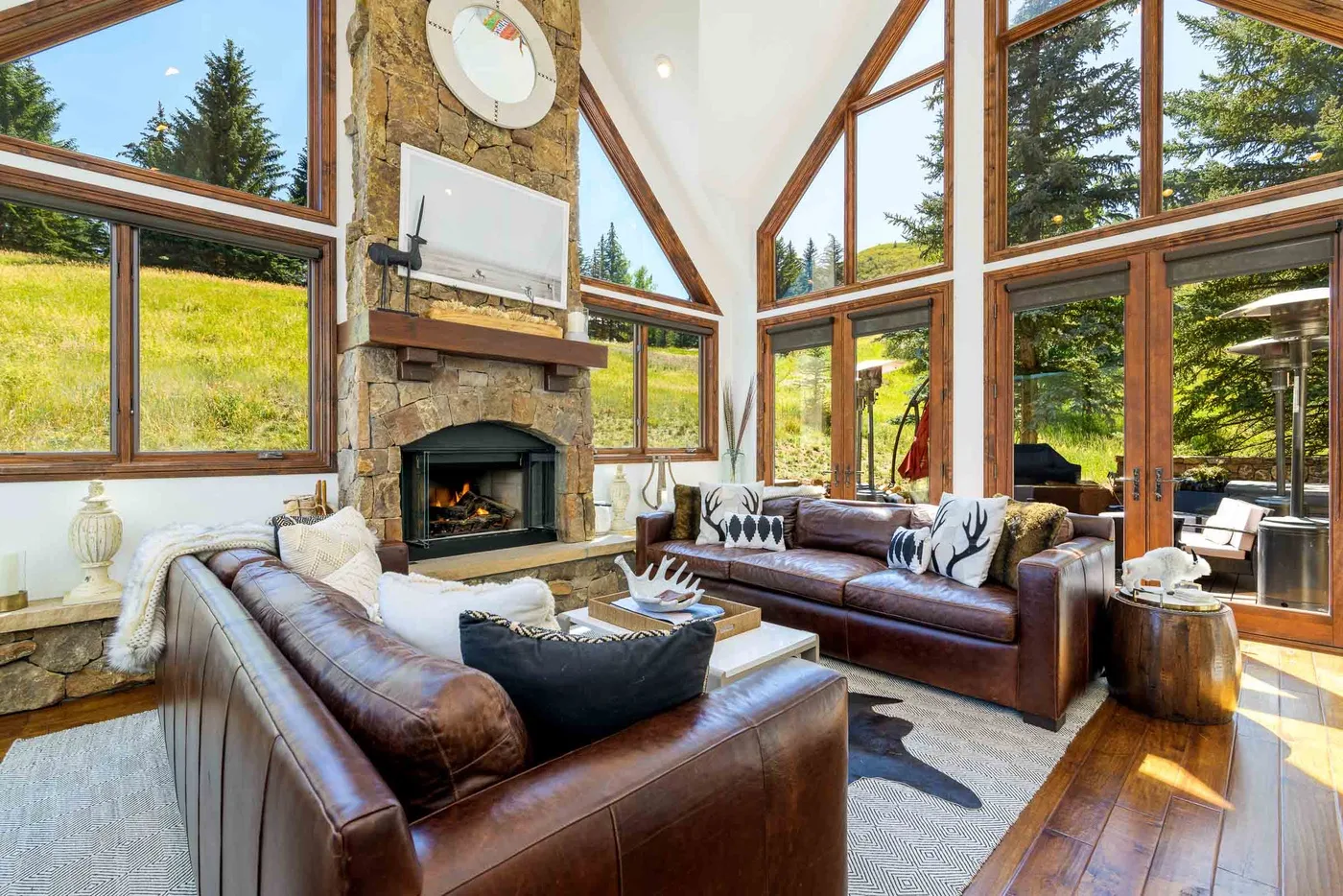 Una sala de estar con asientos de cuero, una chimenea de piedra y grandes ventanas.