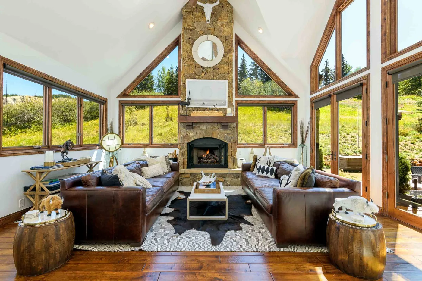Una luminosa sala de estar con grandes ventanas, asientos y una chimenea de piedra.