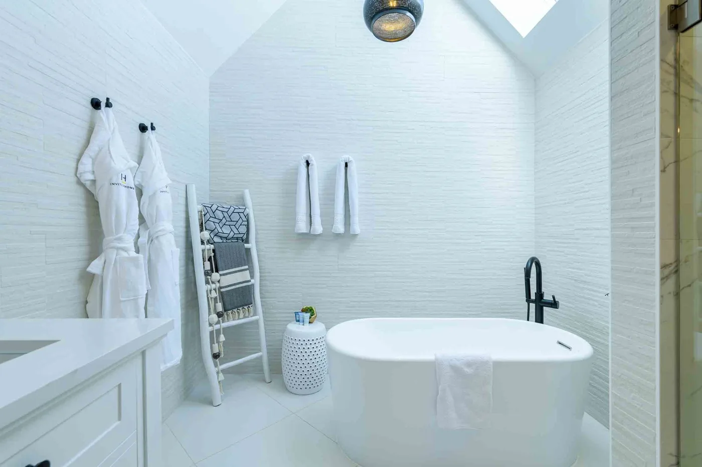 Un baño luminoso cuenta con una bañera exenta y toallas blancas.