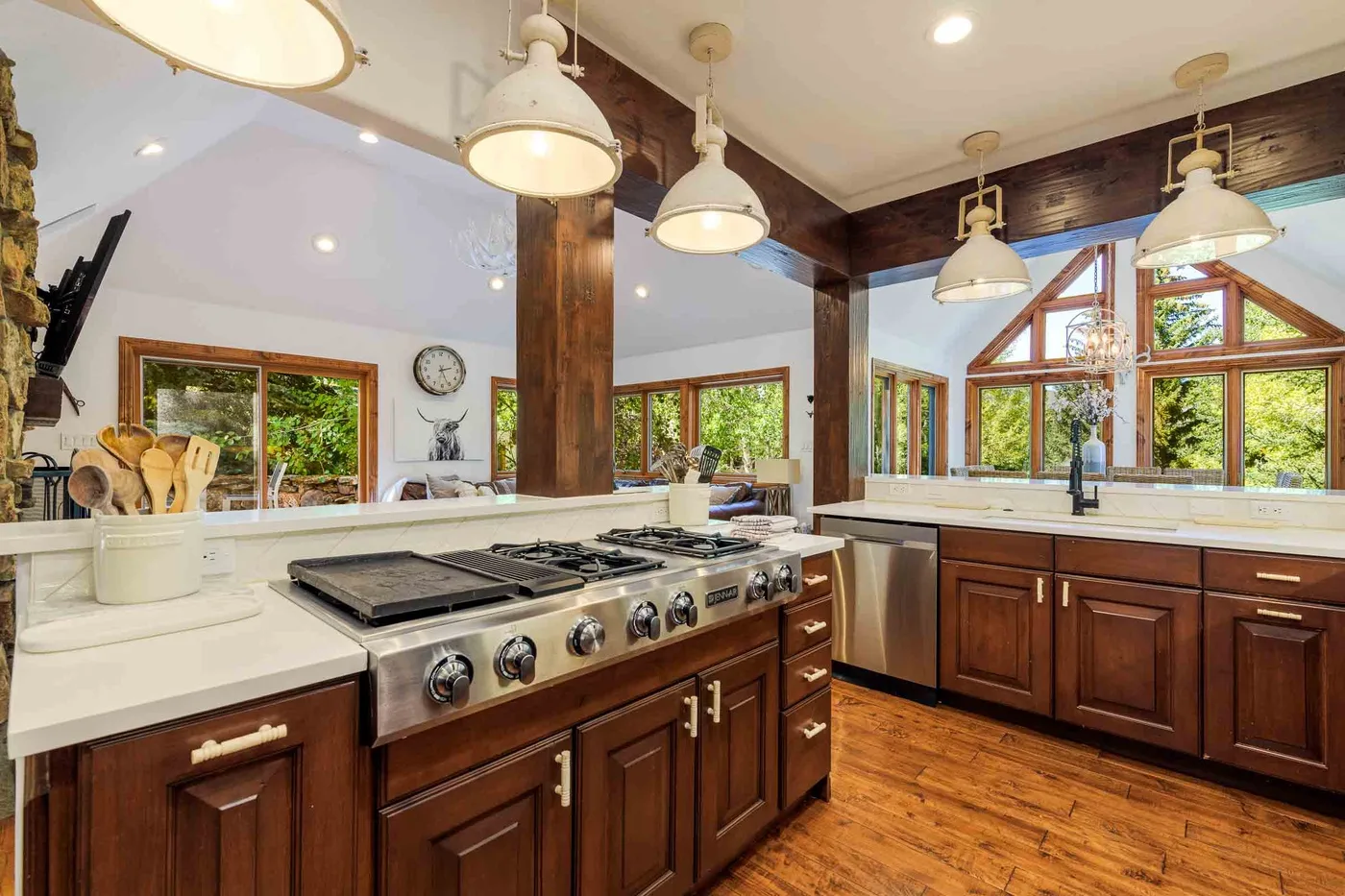 Una cocina amplia con gabinetes de madera oscura, una estufa grande y ventanas con vista a la vegetación.