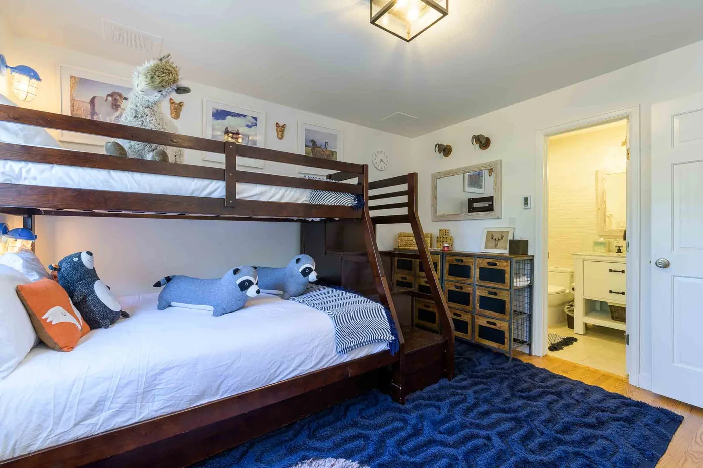 Un dormitorio con literas, peluches y una alfombra azul.