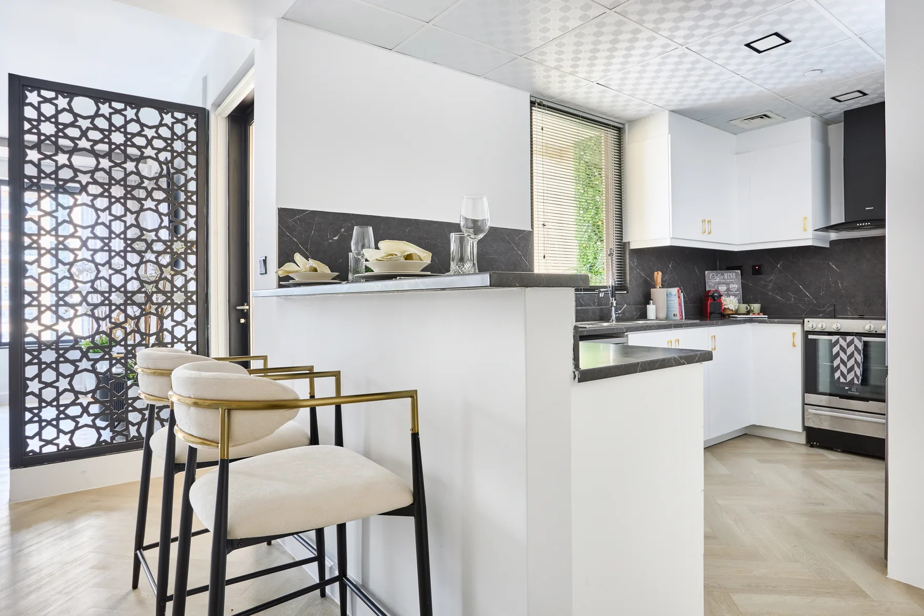 Una cocina moderna con barra, asientos y una celosía decorativa junto a la entrada.