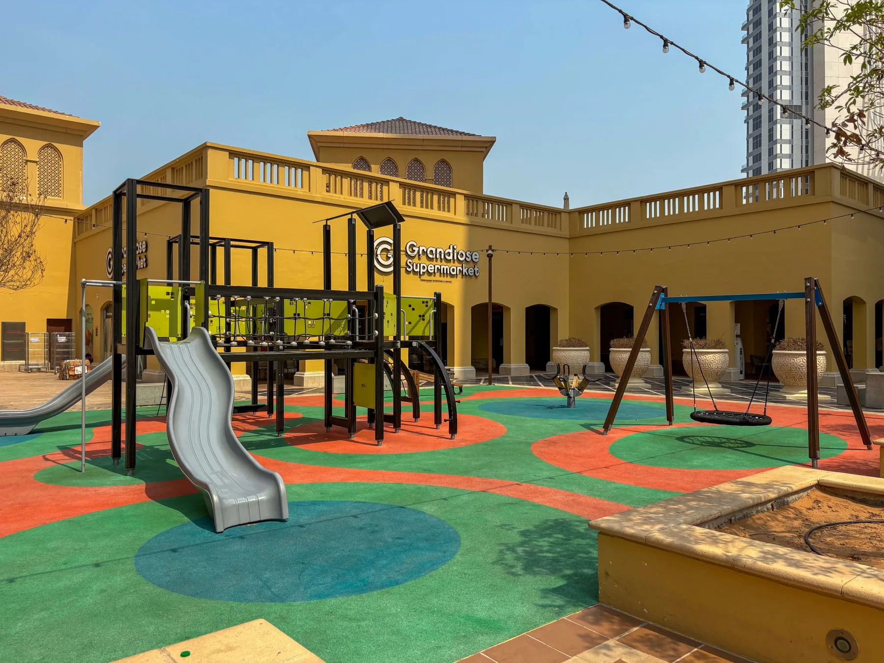Un parque infantil al aire libre y colorido, con estructura para trepar, tobogán y columpios.