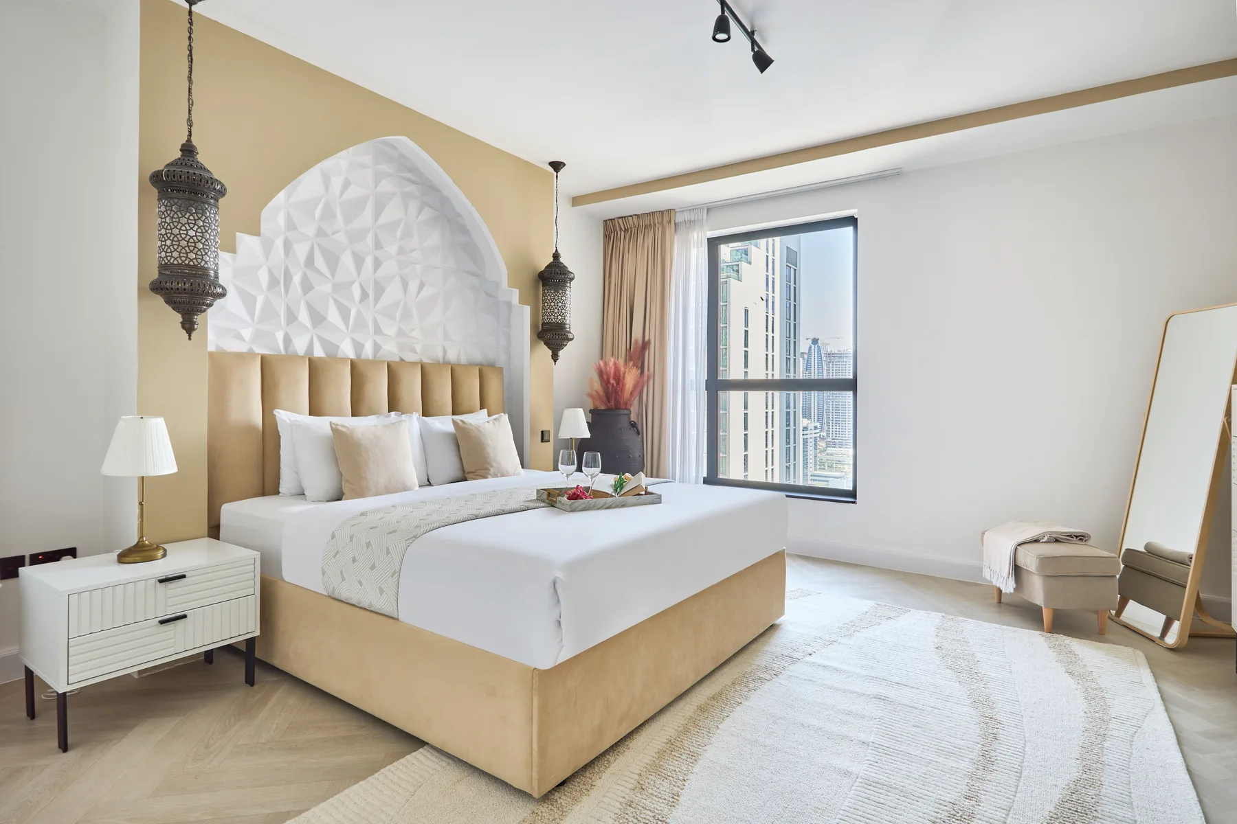 Un dormitorio luminoso con una cama grande bajo un panel decorativo blanco.