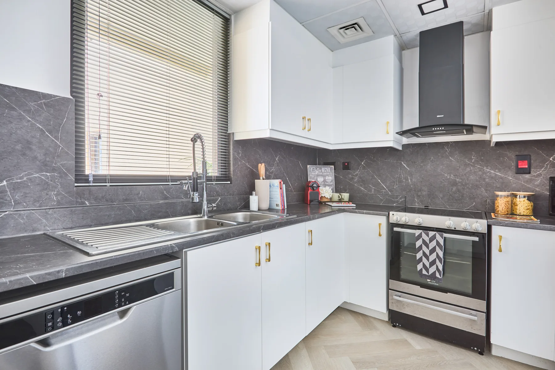 Una cocina luminosa con gabinetes blancos, encimeras oscuras y un horno de acero inoxidable.