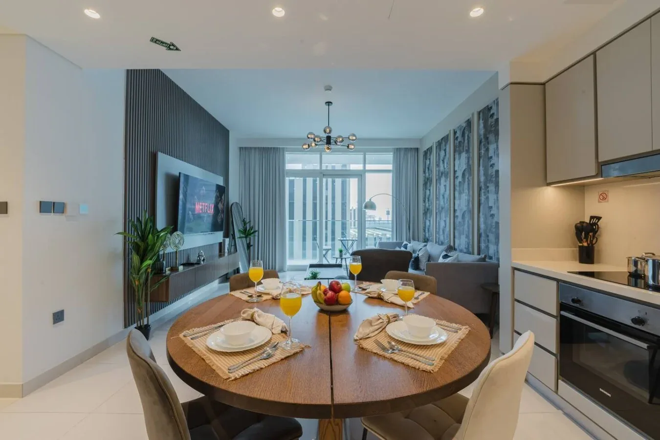 Un comedor y sala modernos, con la mesa puesta y grandes ventanales.