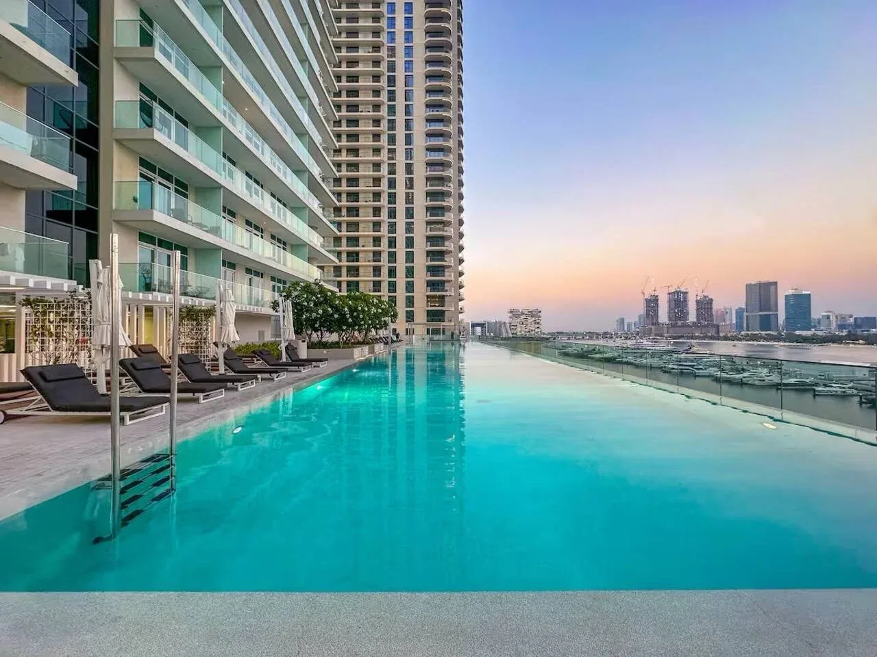 Una piscina en la azotea junto a un edificio alto, con asientos junto al borde.