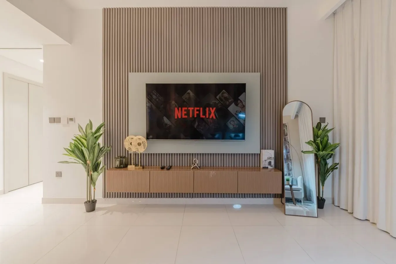 Una sala luminosa tiene un televisor montado en la pared sobre una consola baja.