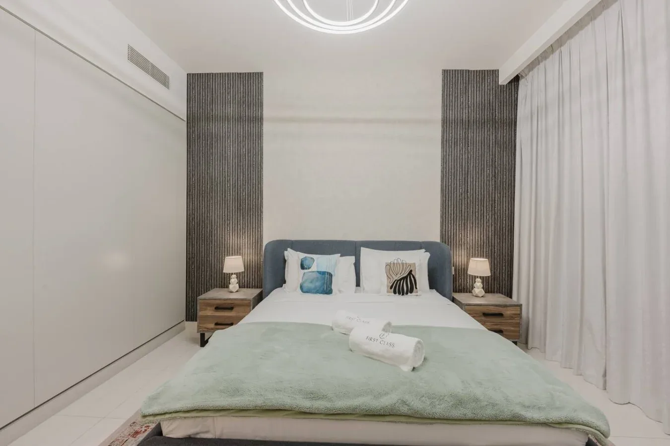 Un dormitorio con una cama, mesitas de noche y cortinas largas.