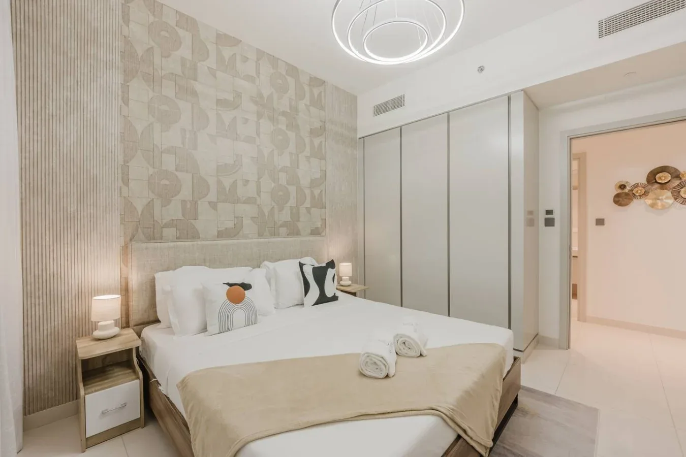 Un dormitorio con una cama bien tendida y papel tapiz estampado.
