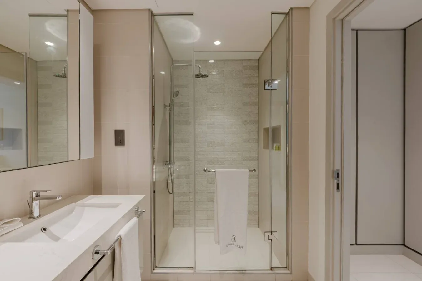 Un baño moderno con ducha de vidrio y un lavabo blanco.