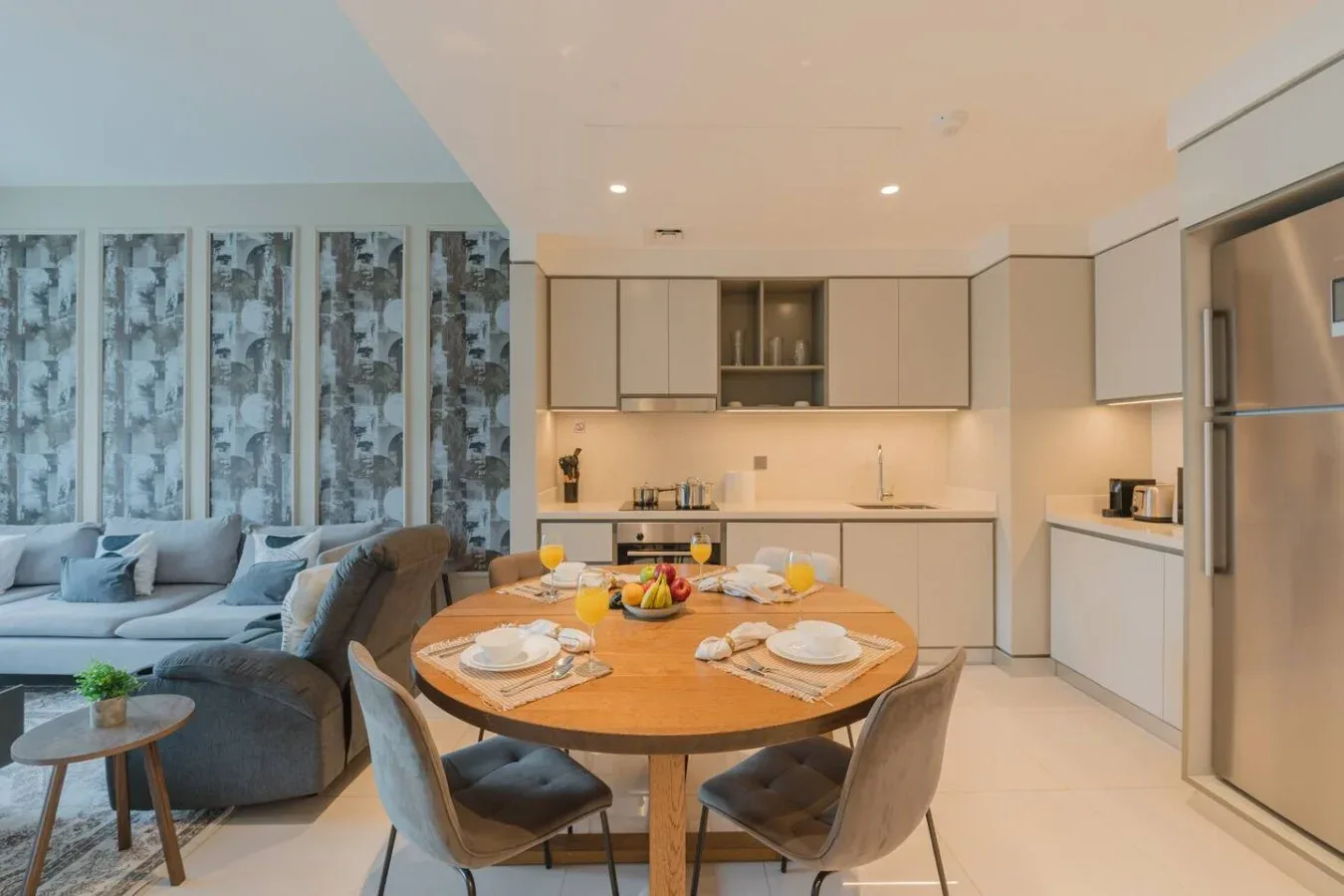 Comedor con una mesa redonda junto a una sala de estar y una cocina abierta.