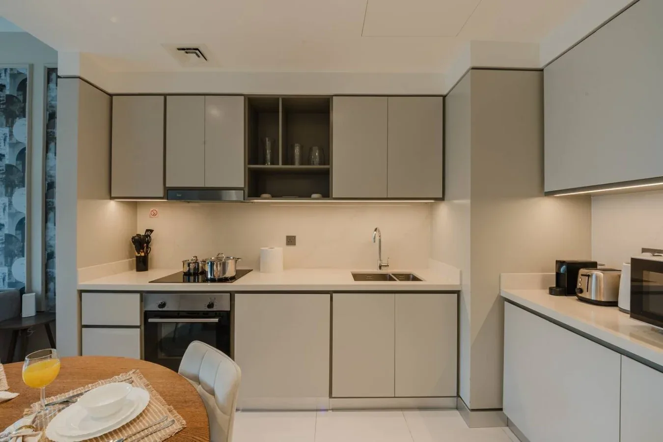 Una cocina moderna con gabinetes claros, una encimera y una pequeña mesa de comedor.