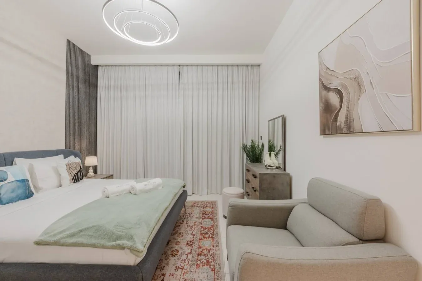 Un dormitorio con cama, asientos y cortinas de cuerpo entero.