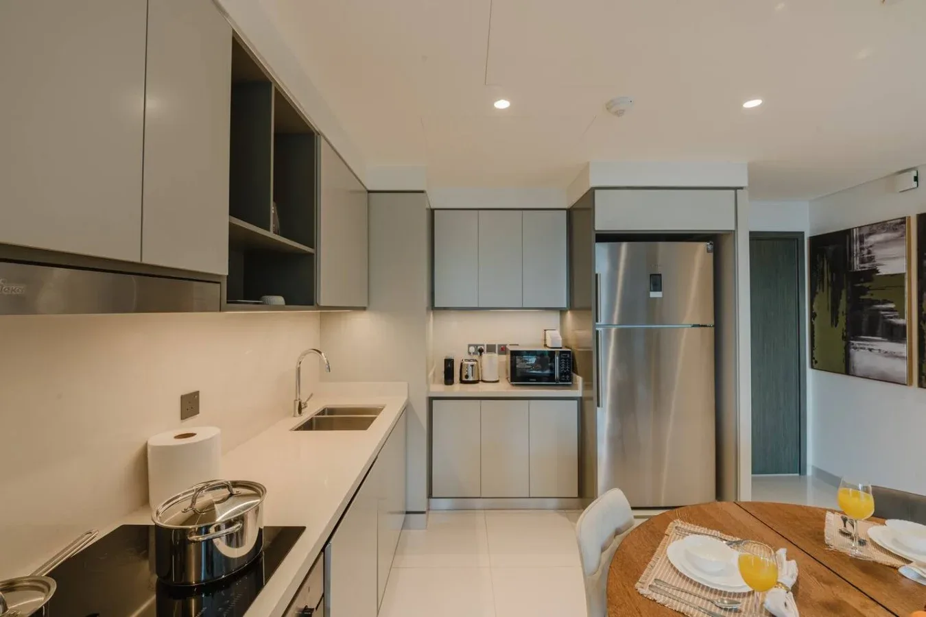 Una cocina moderna con gabinetes claros, un refrigerador de acero inoxidable y una mesa de comedor.