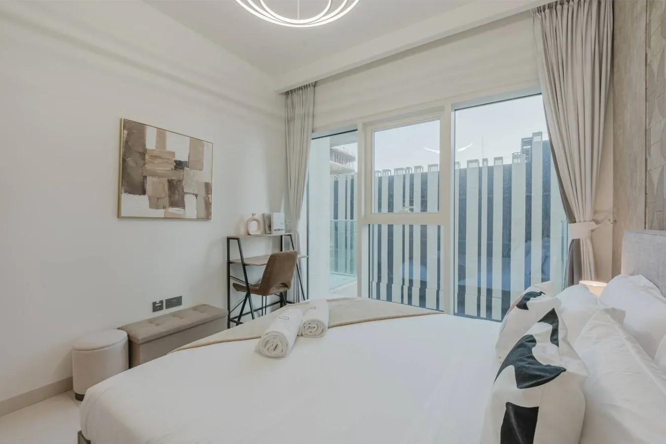 Un dormitorio luminoso con una cama bien tendida y grandes puertas de cristal.