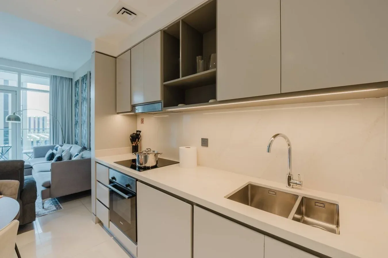 Una cocina moderna con fregadero y zona de cocción junto a una sala de estar.