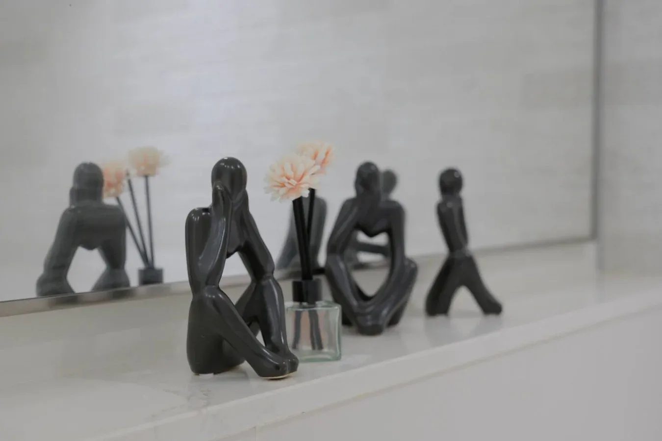 Figuras decorativas y pequeños arreglos florales están sobre una repisa blanca.