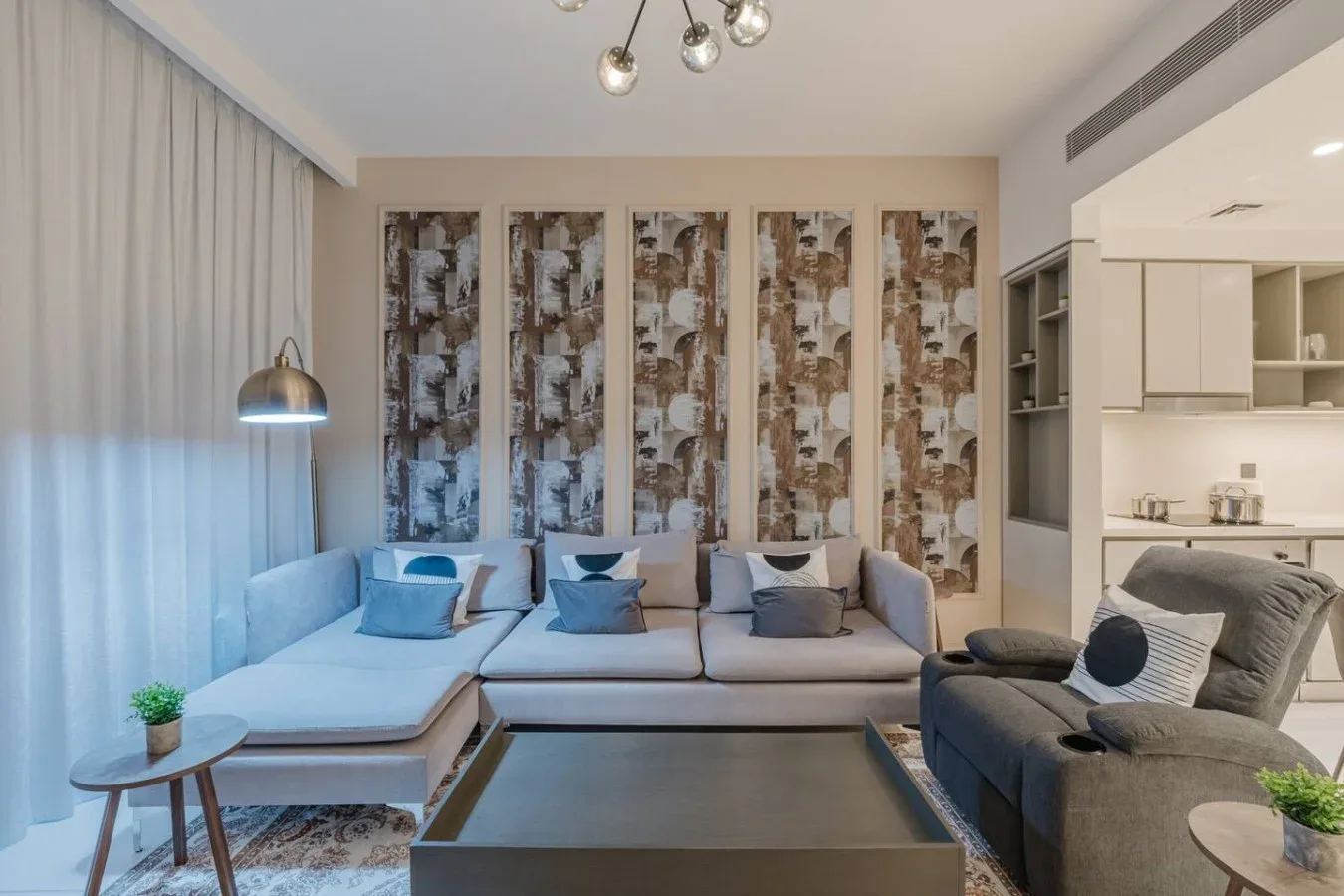Una sala de estar con asientos seccionales, una mesa de centro y paneles decorativos altos en la pared.