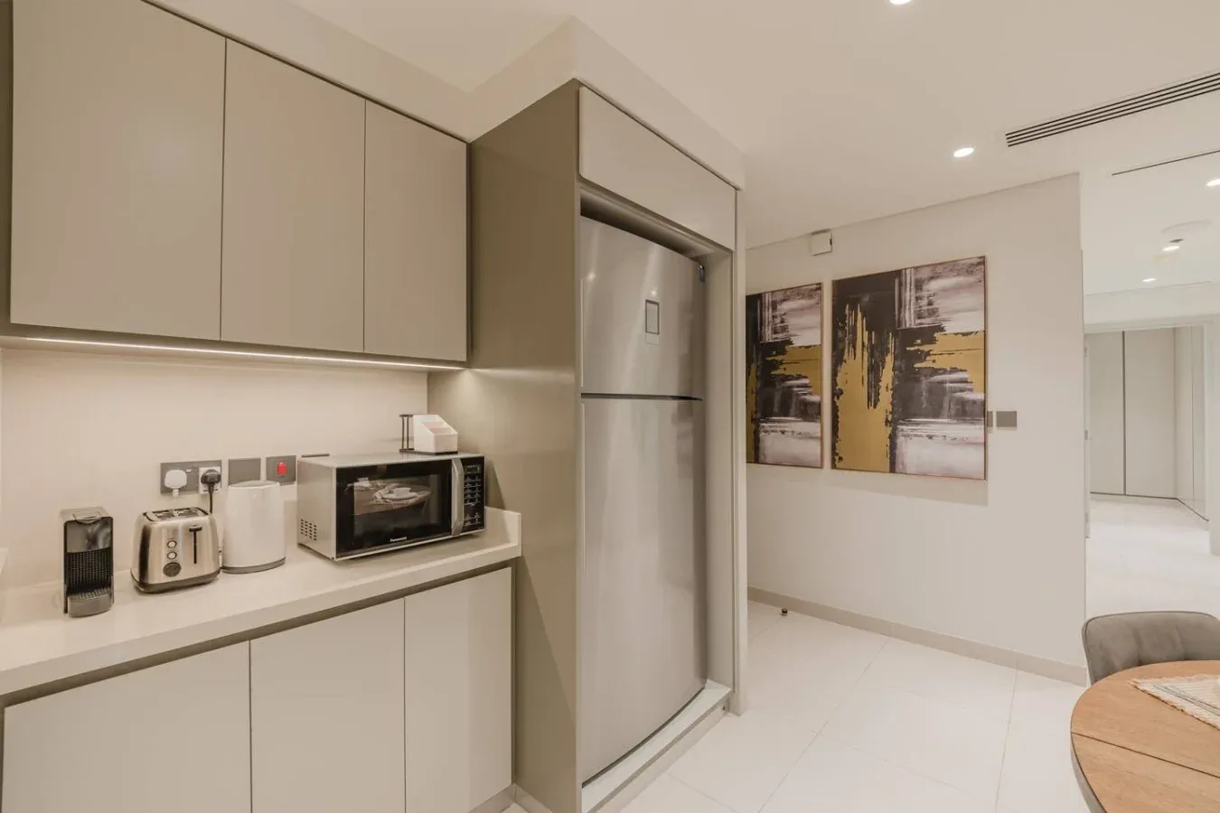 Una cocina moderna con gabinetes claros, un refrigerador y electrodomésticos sobre la encimera.