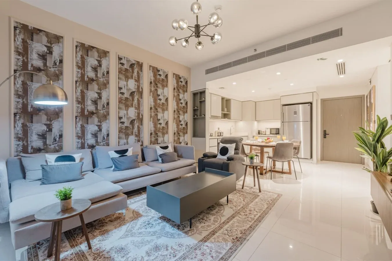 Una sala luminosa con asientos azules y una cocina abierta con comedor.