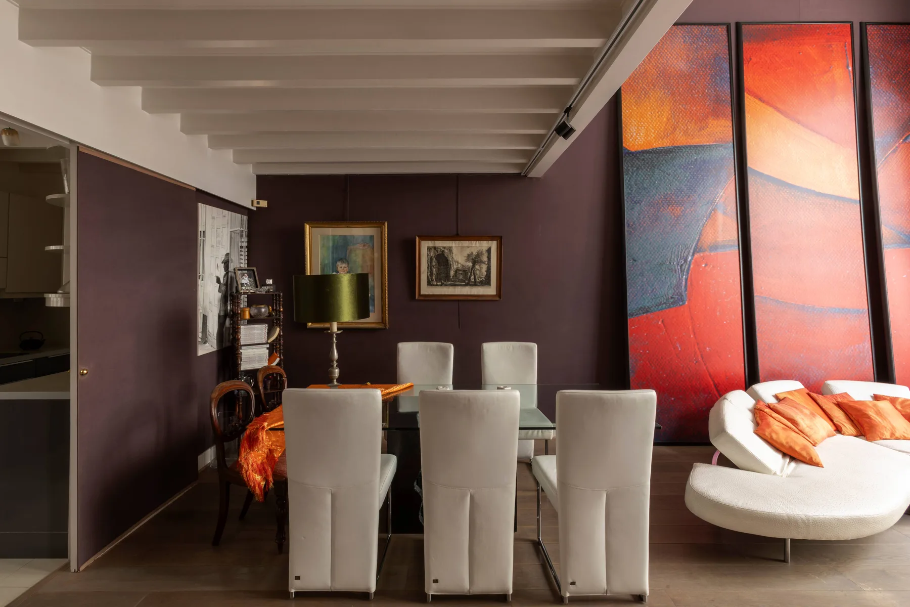 Un comedor con una mesa, asientos tapizados y arte colorido en la pared.