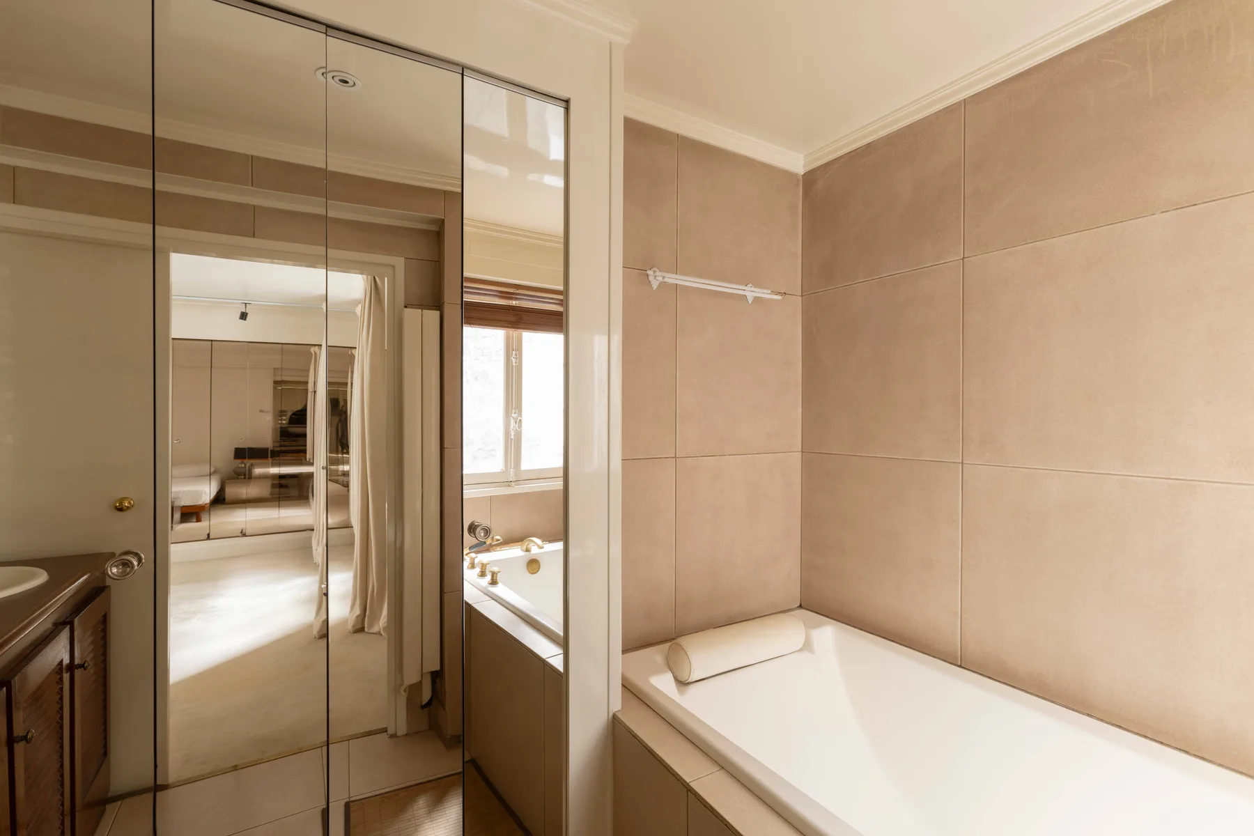 Un baño con una bañera junto a paneles espejados y un lavabo.