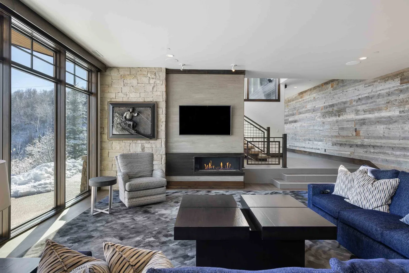 A contemporary living room with large windows, a fireplace, and seating.