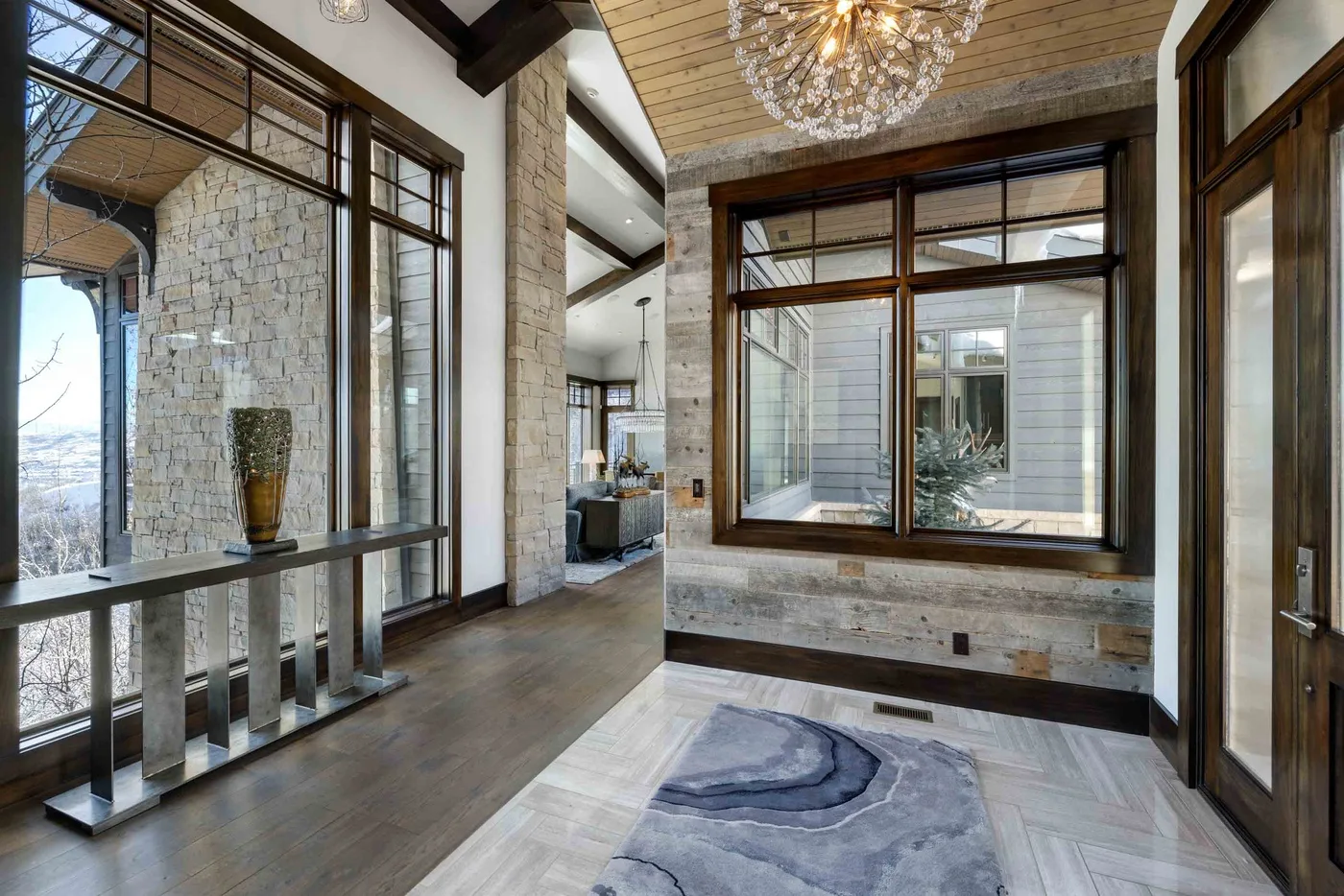 A bright entry hall with tall windows and a stone accent wall.