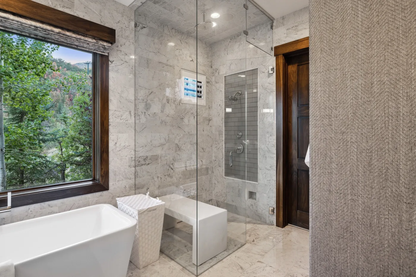 A marble bathroom with a bathtub beside a glass shower.