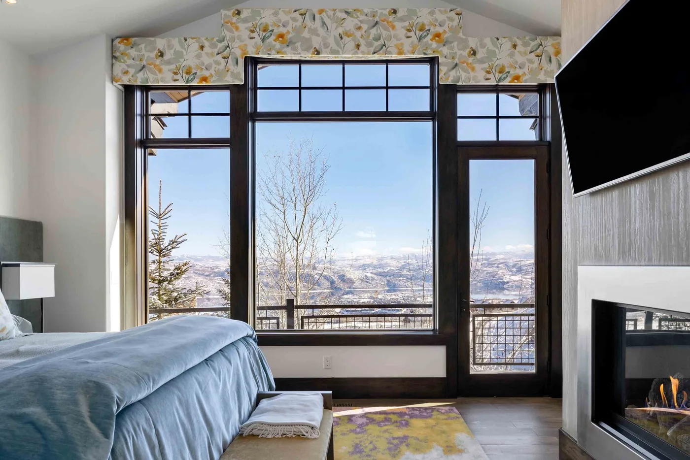 A bedroom with a large window overlooking a snowy landscape.