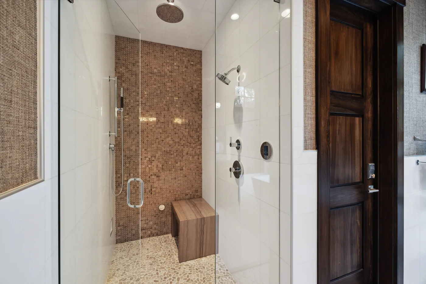 A modern bathroom shower with glass panels and a tiled accent wall.