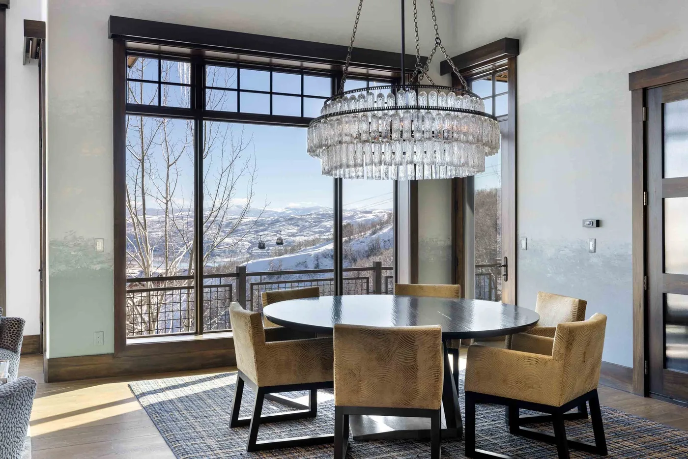 A dining area with a round table and large windows overlooking a snowy landscape.