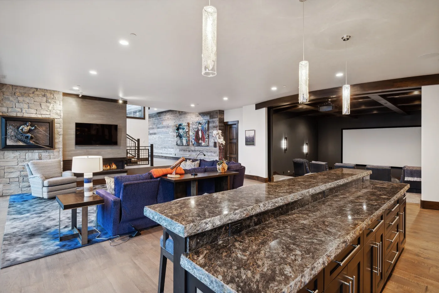 An open-plan living room and kitchen with a large stone island and lounge seating.