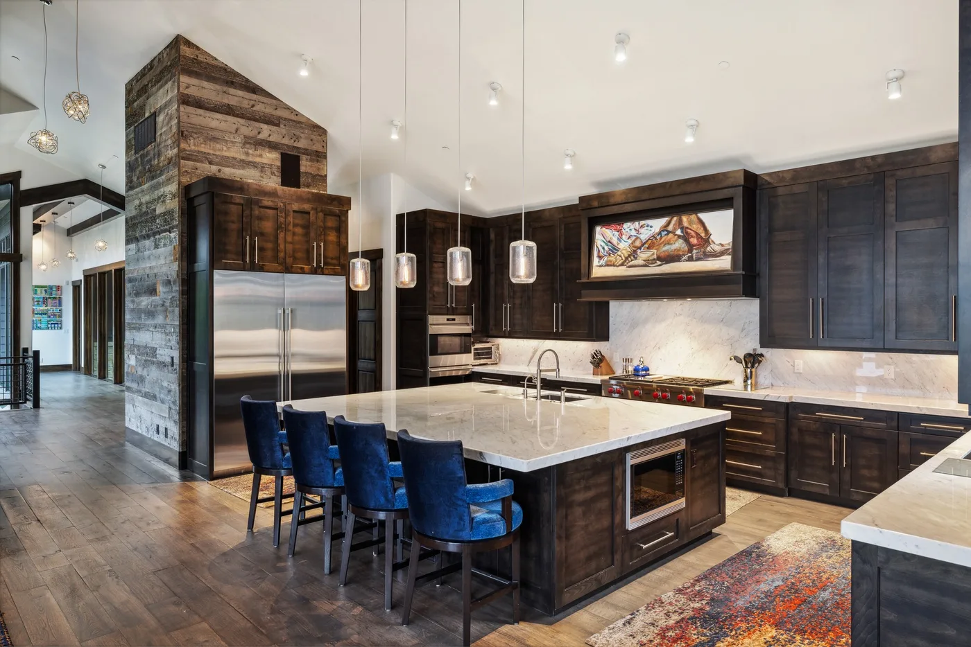A spacious kitchen with dark cabinetry, a central island, and blue seating.