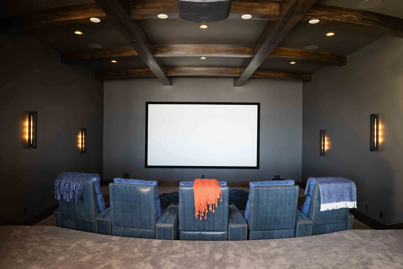 A home theater with rows of blue seating facing a large screen.