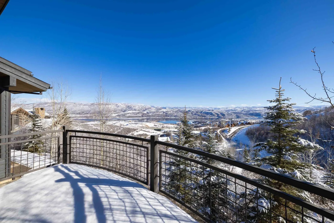 A snow-covered outdoor deck overlooks a winding river and winter landscape.