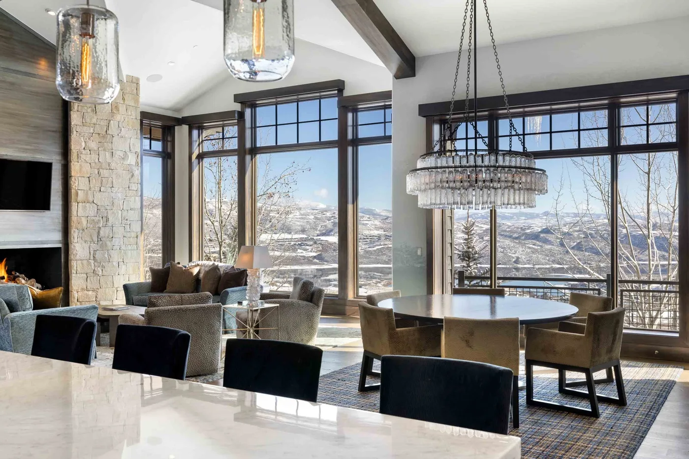 A bright living and dining area with large windows and a table surrounded by seating.
