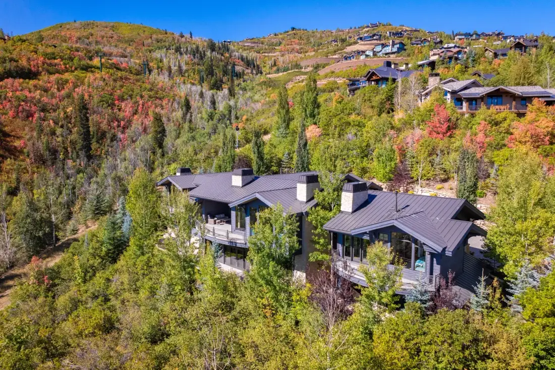 Aerial view of hillside homes surrounded by colorful autumn trees.
